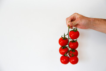 Young woman holding a branch of beautiful juicy organic red cherry tomatoes. Woman with shiny polished glossy vegetables. Clean eating concept. Vegetarian summer detox diet. Copy space, flat lay.