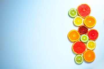 Close up image of juicy organic assorted sliced citrus fruits, visible core texture, bright paper textured background, copy space. Vitamin C loaded food concept. Top view, flat lay.
