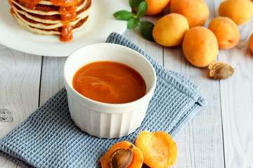 Composition apricot jam on white wooden background. Sweet breakfast.