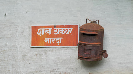 An old rusted Indian post box hanging on a wall