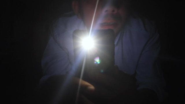 Young Man Shining A Flashlight From A Mobile Phone In The Dark