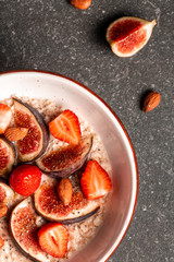healthy breakfast. Bowl of oatmeal with fruits and berries, figs, strawberries and chia seeds, honey, top view, copy space