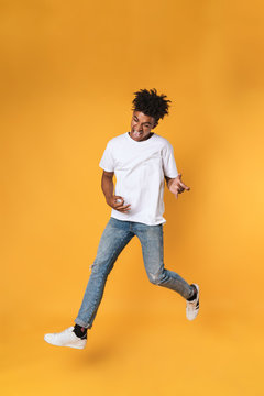 Happy young african guy jumping on yellow