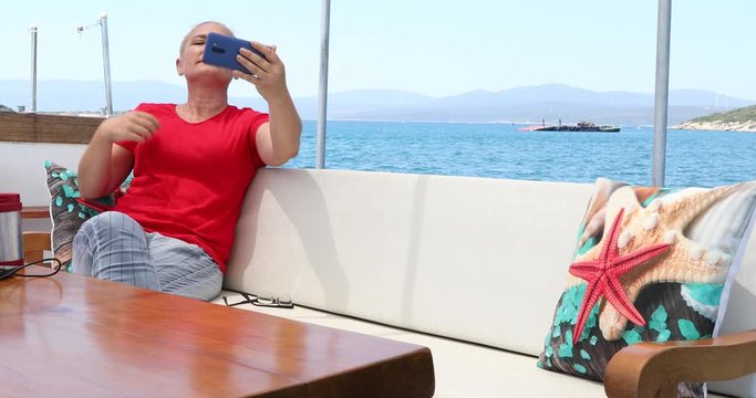 Caucasian blonde woman making selfie photo during summer boat travel