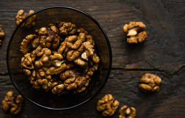 Walnut in a smale plate with scattered shelled nuts and whole nut which standing on a wooden...