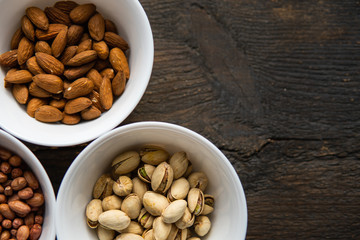 Pistachio, peanut and almond in a small plates which standing on a black table. Nuts is a healthy vegetarian protein and nutritious food.