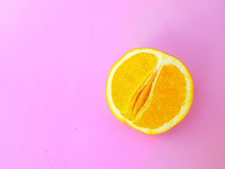 Bright juicy orange on a pink background. A vagina symbol. The concept of sex. Women's personal...