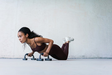 Photo of african american sportswoman working out with push-up stops