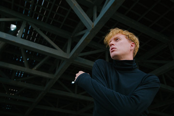 A fashionable look into the distance against the backdrop of metal structures.