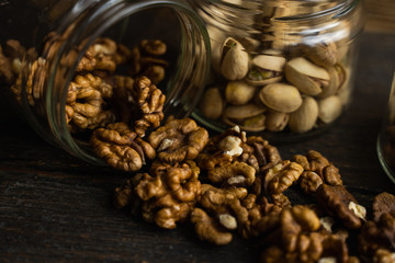 Walnut scattered on the wooden vintage table from a jar. Walnut is a healthy vegetarian protein nutritious food. Walnut kernels and whole walnuts on rustic old wood.