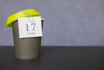 Coffee paper cup with calendar dates for June 17, Summer season. Time for relaxing breaks and vacations.