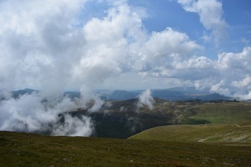 Fototapeta na wymiar fluffy white clouds among the mountain ridges. mist at high altitude