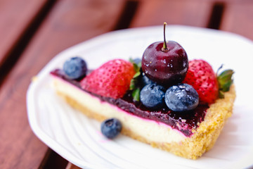 Blueberry cheesecake with fresh berries on white plate