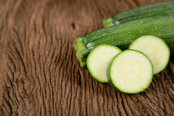 uncooked whole and sliced fresh zucchini on wooden background
