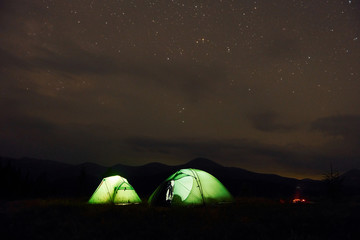 Green tents at night time. Starry sky. Majestic Carpathian Mountains. Beautiful landscape of untouched nature