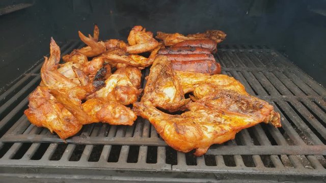 Home cooking - Close  up of chicken wings and sausage  being smoked for extra smoky flavor after previously cooked in gas grill.