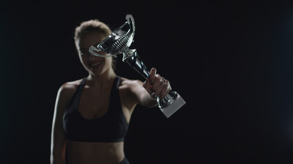 Happy woman champion holding trophy cup in studio. Sport woman winner