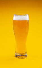 Glass of beer on yellow background