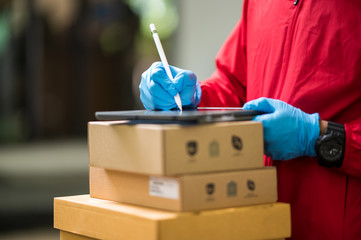 Close up delivery man Wearing blue gloves in red cloth Checking customer boxes for delivery