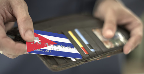 Man pulls plastic bank card with flag of Cuba out of his wallet, fictional card number