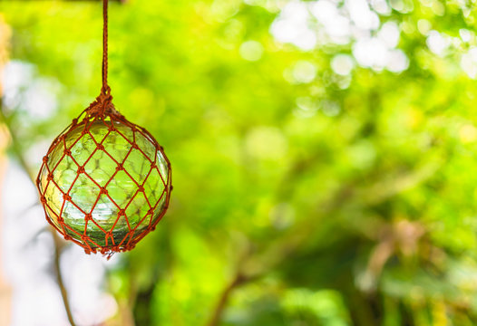 Close-up on japanese traditional handmade glass fishing floats Bindama or Ukidama in a nets hanging against a bokeh background.