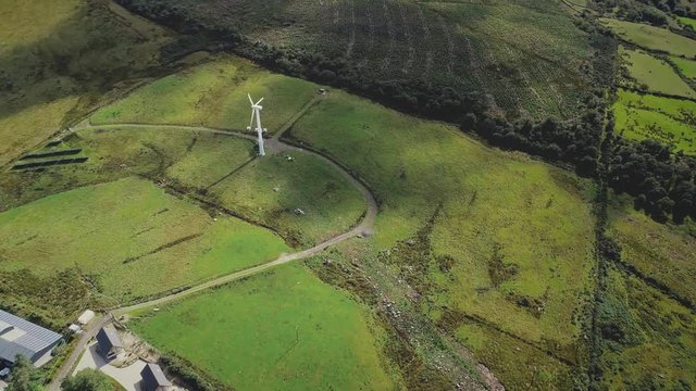 Ireland aerogenerator windmill hyperlapse aerial view. Wind turbine on green valley with solar panels and white houses. Beautiful summer landscape. Ecological environment concept plot shot in 4K, UHD