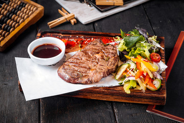 Grilled juicy steak with sauce and salad