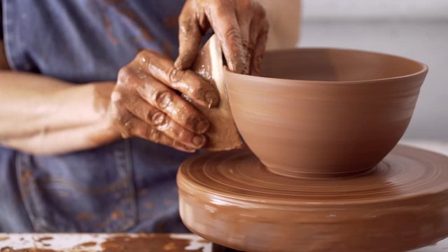 Man at pottery wheel making clay bowl
