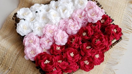Artificial flowers made out of beautiful fabric texture in red, soft pink, and broken white colors