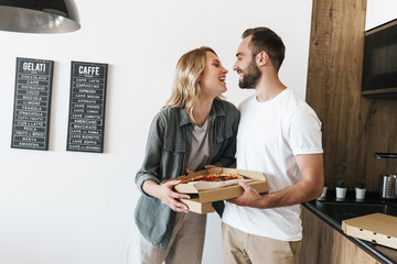 Image of young happy couple laughing while holding pizza