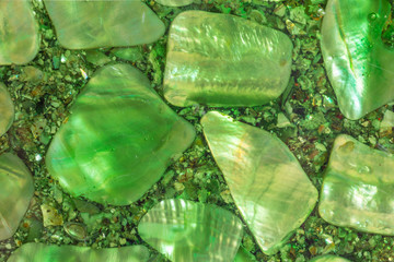 Green polished stones encased in clear resin, macro view.  Up close photo of iridescent rocks, with...