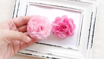 Handmade pink rose flowers on a white photo frame as background