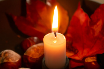 Kerze mit Kastanien und Blättern