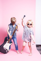 Pop Culture: Children a boy with a guitar and a girl with a microphone pretend to be popular musicians and perform a home concert.