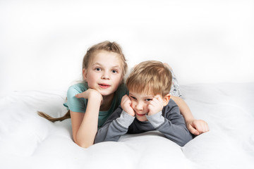 Friendship: a boy and a girl are lying on the bed propping their chin in their hand.
