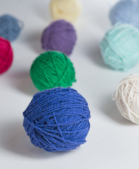 Colorful yarn balls arranged on a white surface.  A variety of colors and sizes of yarn ready to be knit or crocheted into a number of different items.  