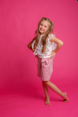 cute girl with long hair posing on a pink background in the Studio