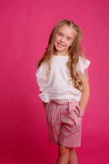 cute girl with long hair posing on a pink background in the Studio
