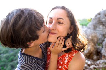 Portrait of a smiling boy hugging mom, a woman with a child on top of a mountain.