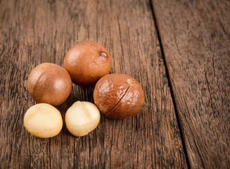 Macadamia nuts, isolated on wood background. Shelled and unshelled macadamia.