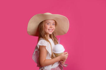 portrait of a small blonde in a hat on a pink background with a can of cooling cocktail.