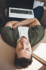 Obraz premium Relaxing caucasian man with a laptop lying on the sofa after working online
