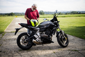 Fototapeta na wymiar A middle-aged man enjoys with his motorcycle