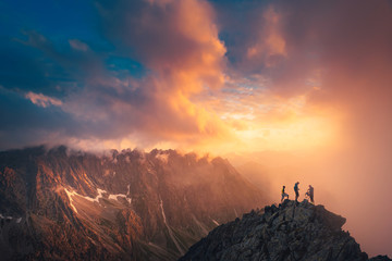 Photo de concept de réussite d& 39 équipe, amis debout ensemble au sommet de la colline, sur un magnifique paysage de montagnes à la lumière dorée du coucher du soleil, espace d& 39 édition orange.