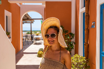 Beautiful woman tourist posing with hat and sunglasses in the courtyard of a typical house of the Aeolian Islands, summer vacation.