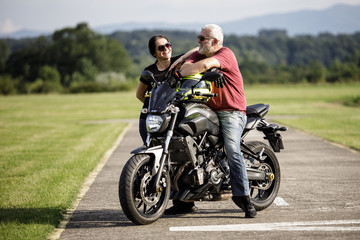 A middle-aged man and his girl friend enjoys with his motorcycle