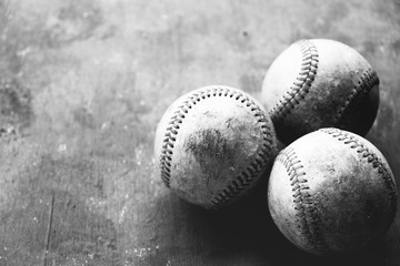 Group of old used baseballs on blurred grunge texture background.