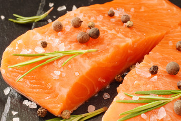 Salmon fish raw uncooked closed up with rosemary leaf and pepper