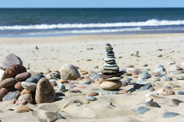 Fototapeta na wymiar Sea stones are stacked on the sand. A pyramid of sea stones on the beach.