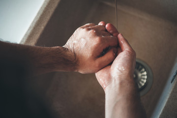 Upper view photo of a caucasian man washing his hands with soap during the epidemic situation